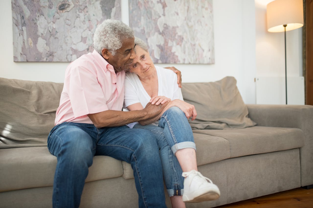Senior couple embracing warmly on a sofa at home, showcasing love and togetherness.